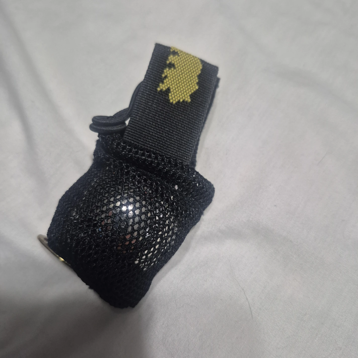 Black bell in a mesh pouch with drawstring and logo strap