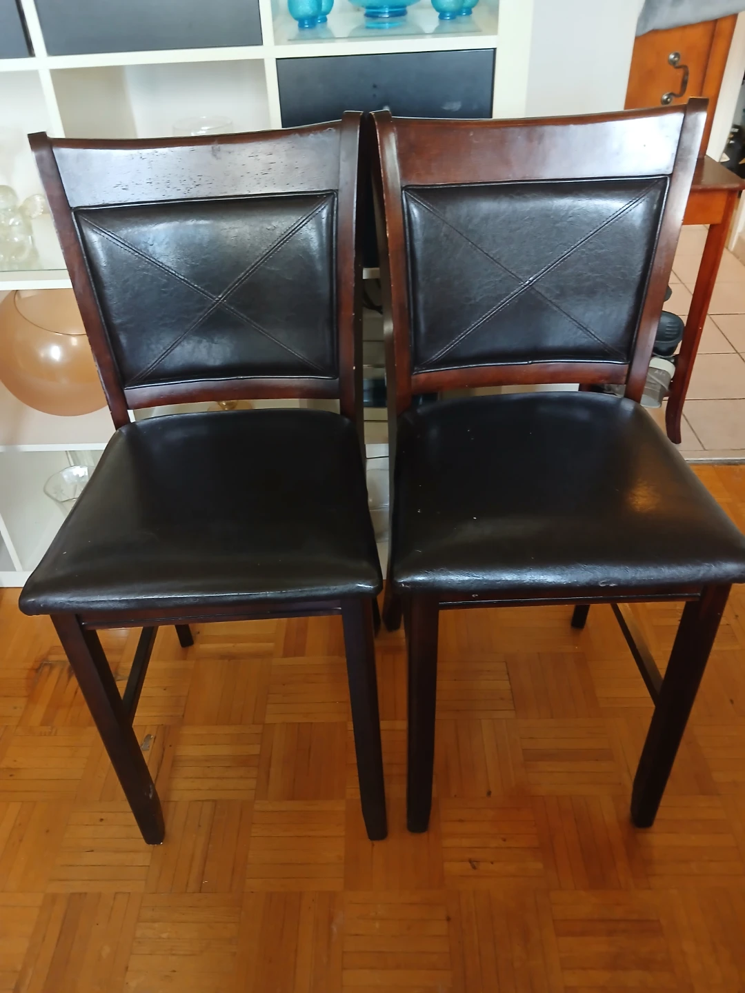 Pair of dark wood dining chairs with black faux leather seats