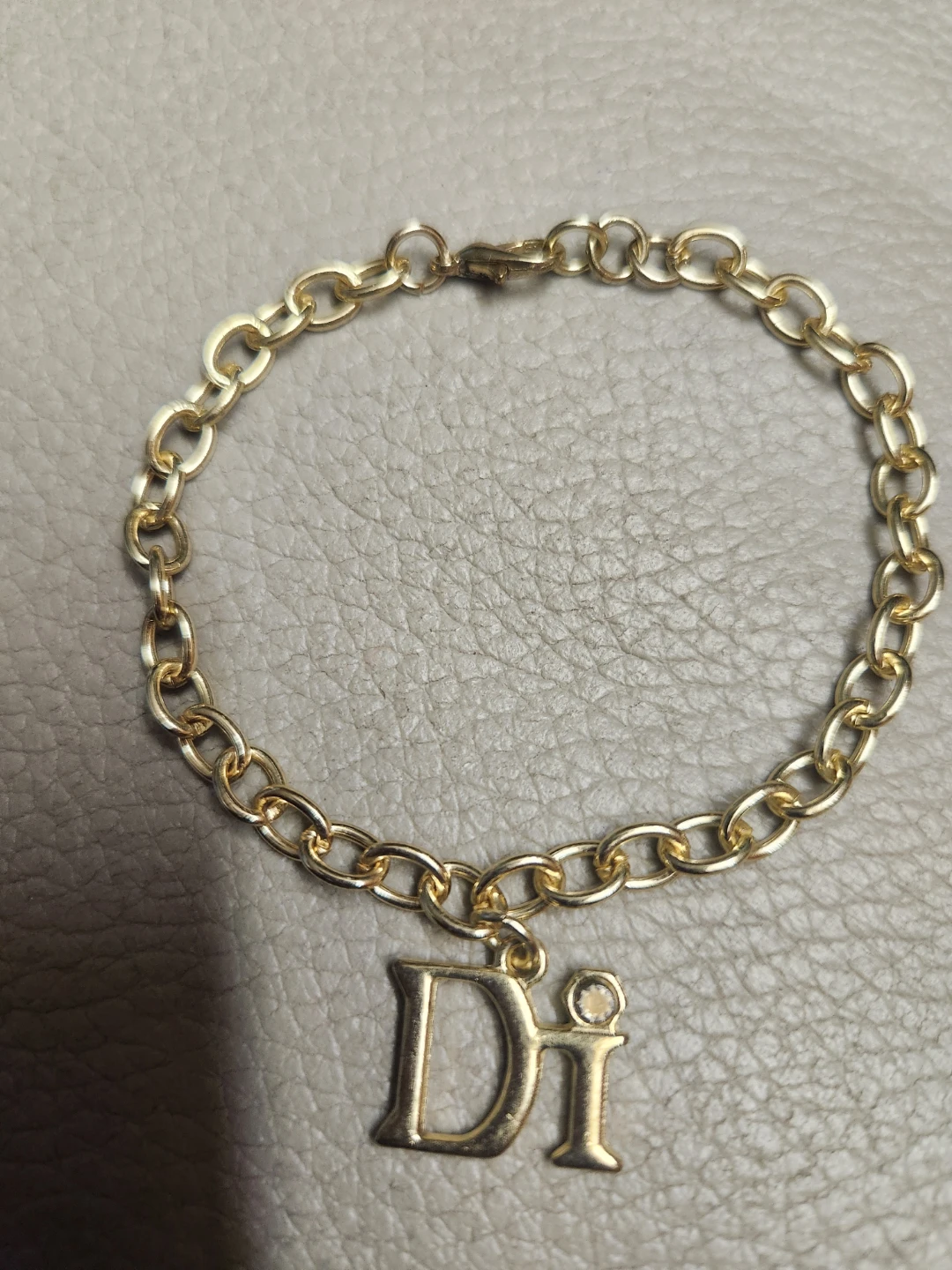 Gold tone charm bracelet with 'Di' initial