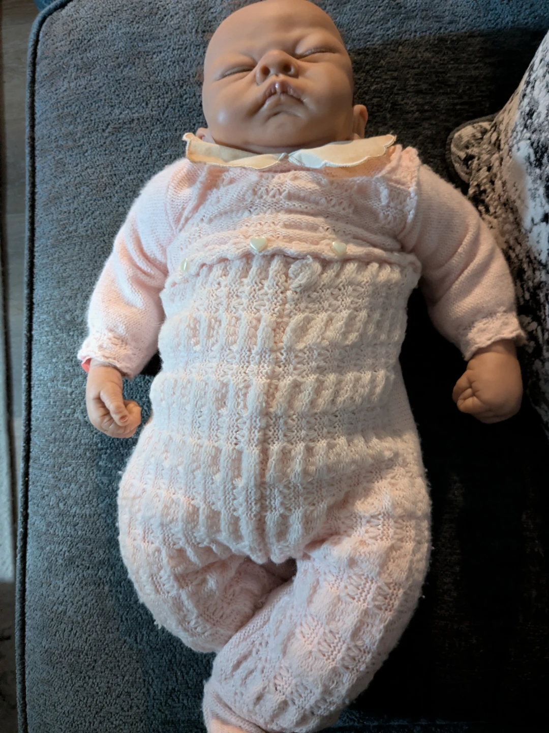 Realistic sleeping baby doll in pink knit outfit