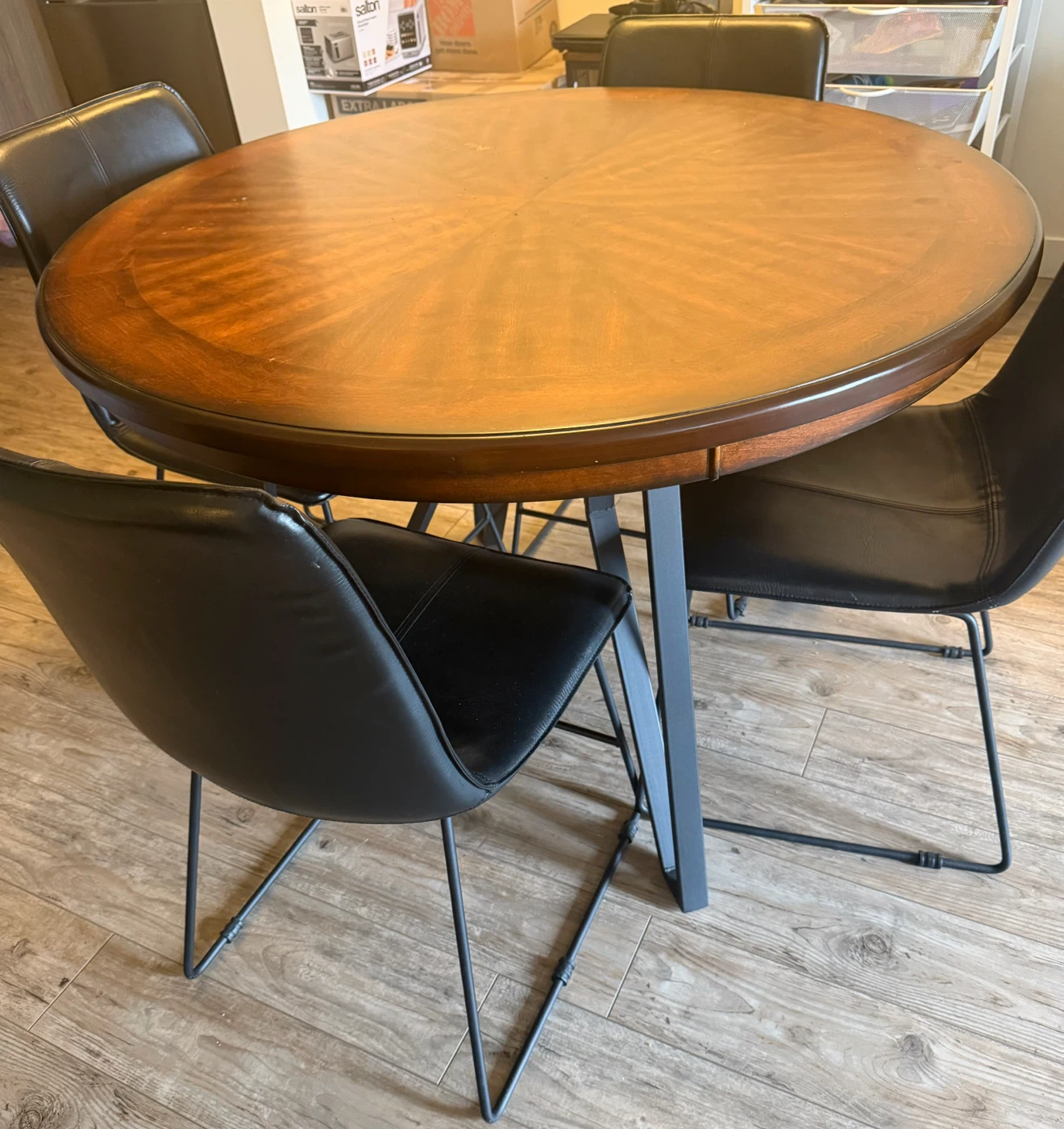 Round cherry wooden dining table with four black chairs