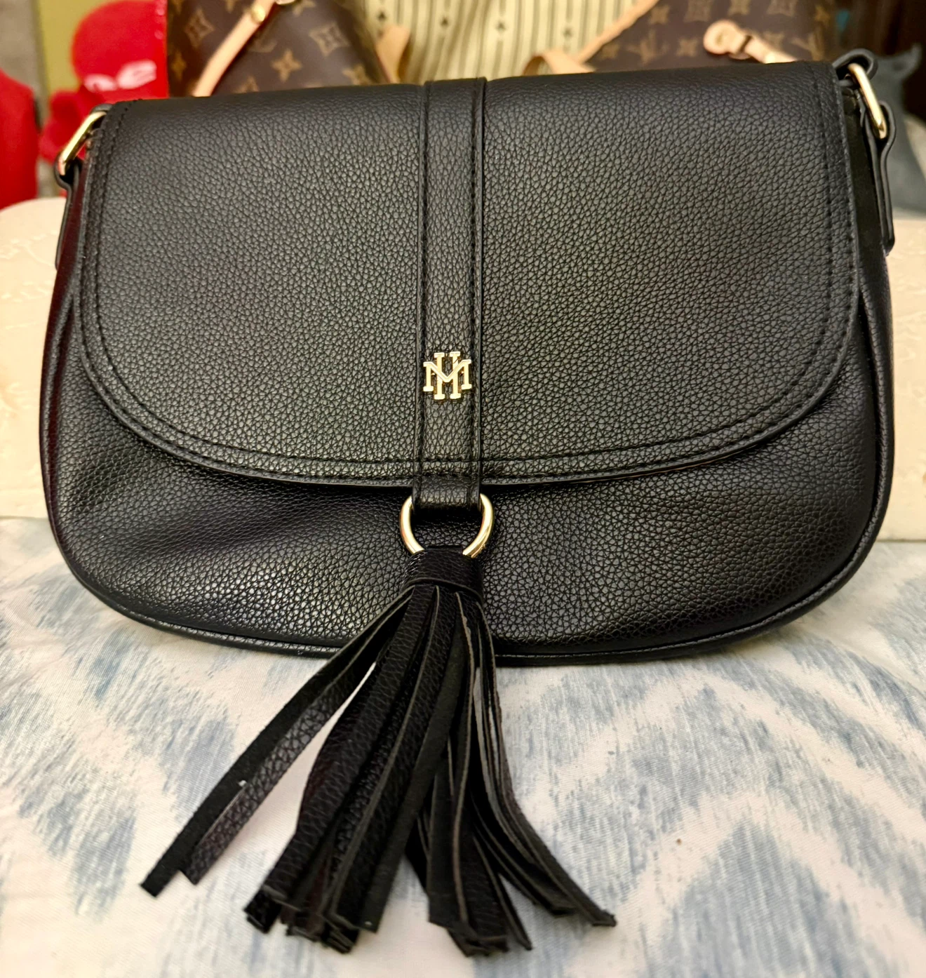 Black crossbody bag with tassel and gold logo