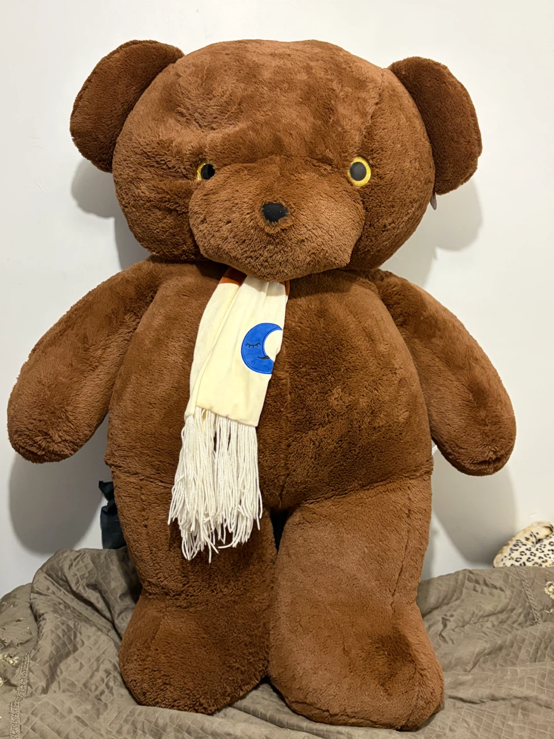 Large brown plush teddy bear with moon scarf