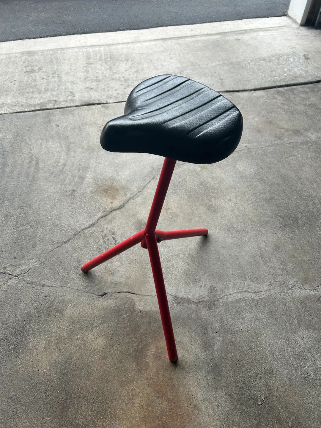 Red tripod stool with black bicycle seat