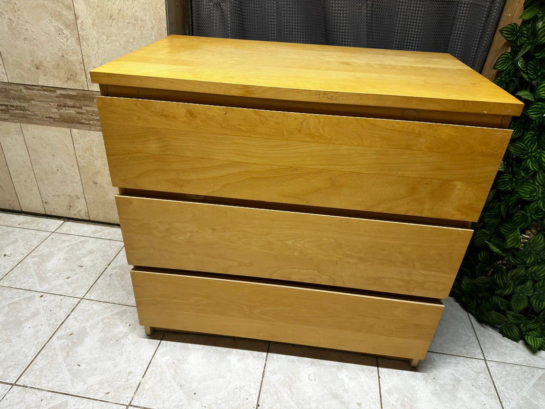 Three-drawer light wood wood dresser.
