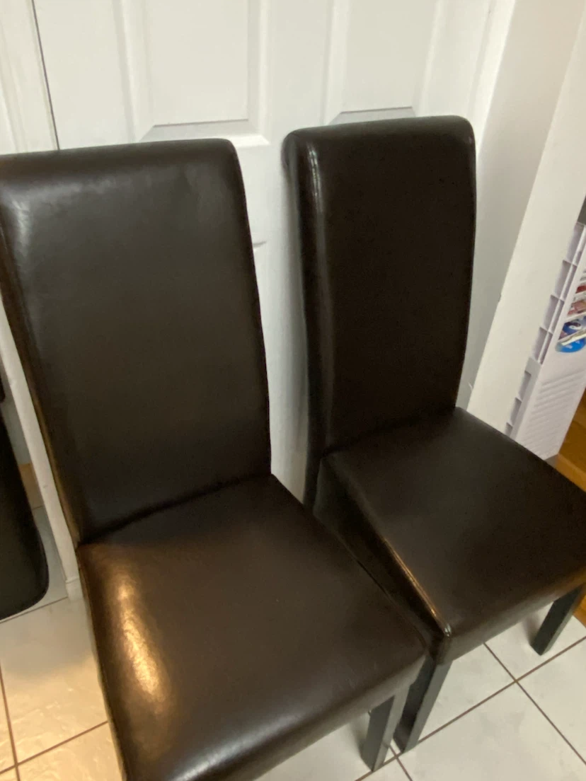 Two dark brown faux leather dining chairs