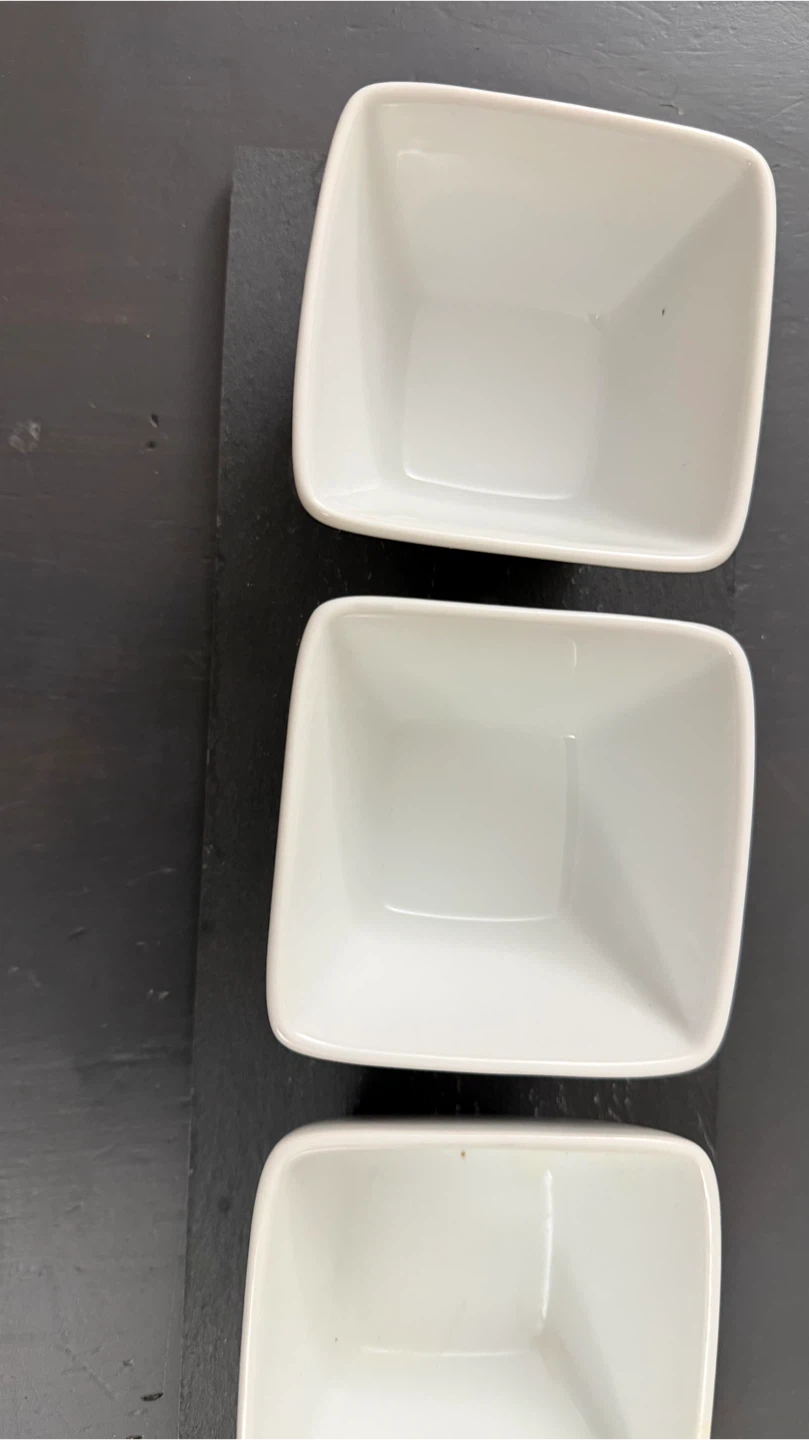 Three white ceramic dipping bowls with slate board