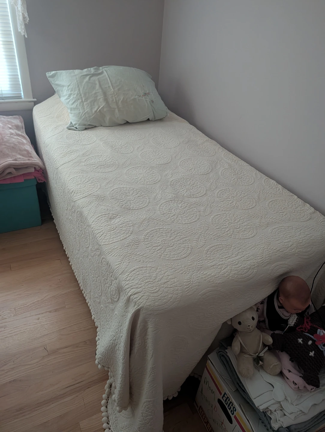 Twin size bed with cream pom-pom quilt