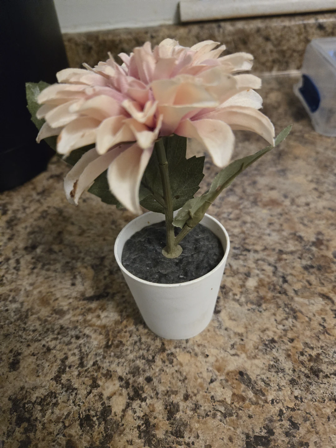 Artificial pink flower in small white pot