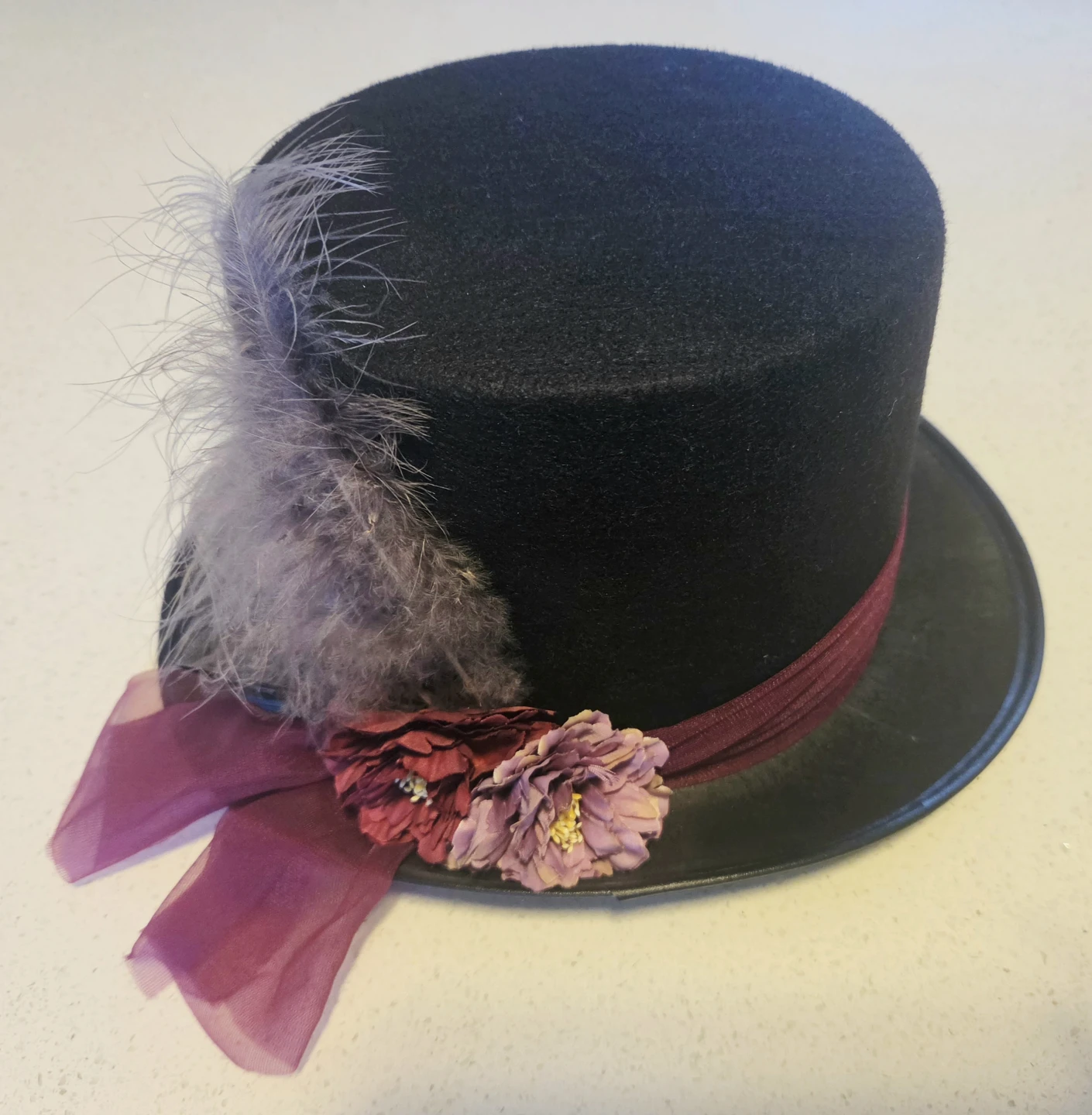 Black top hat with feather and floral trim
