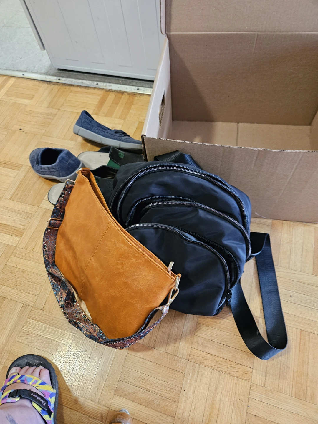 Black backpack and orange handbag with patterned strap