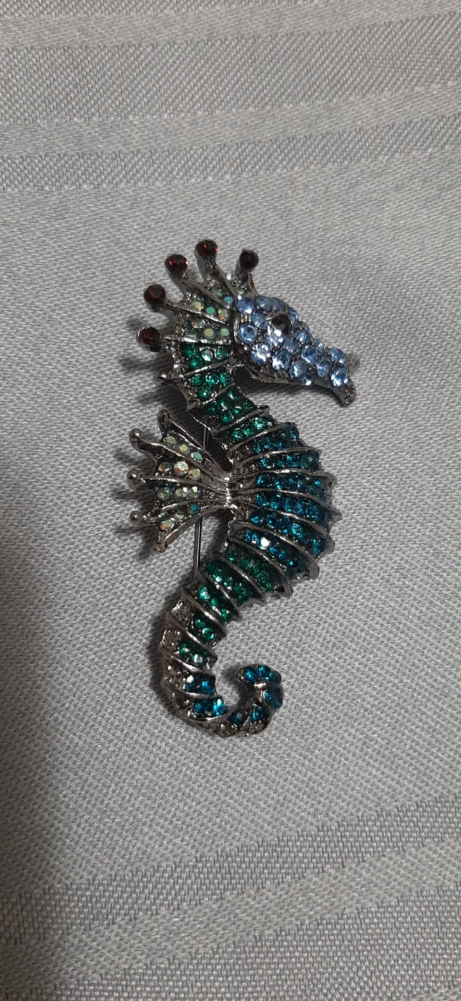 seahorse brooch featuring blue & green stones.