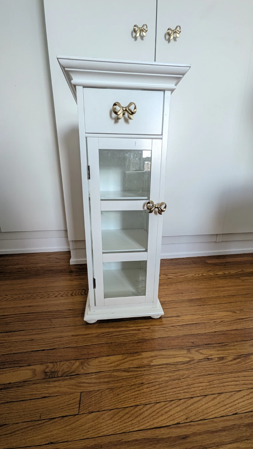 White storage cabinet with gold bow hardware