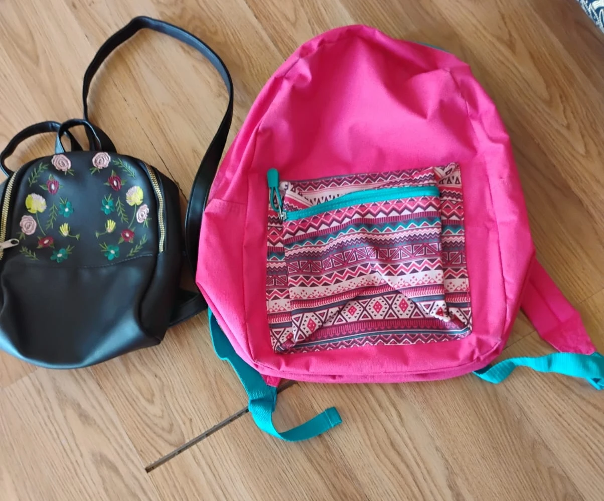 Two backpacks - one black floral and one pink geometric