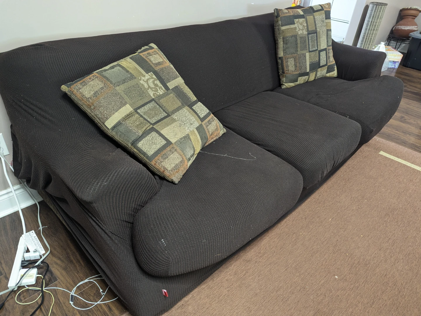 Dark brown three-seater sofa with accent pillows