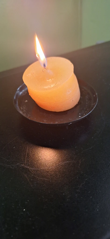 Orange pillar candle on small black plate - photo 2