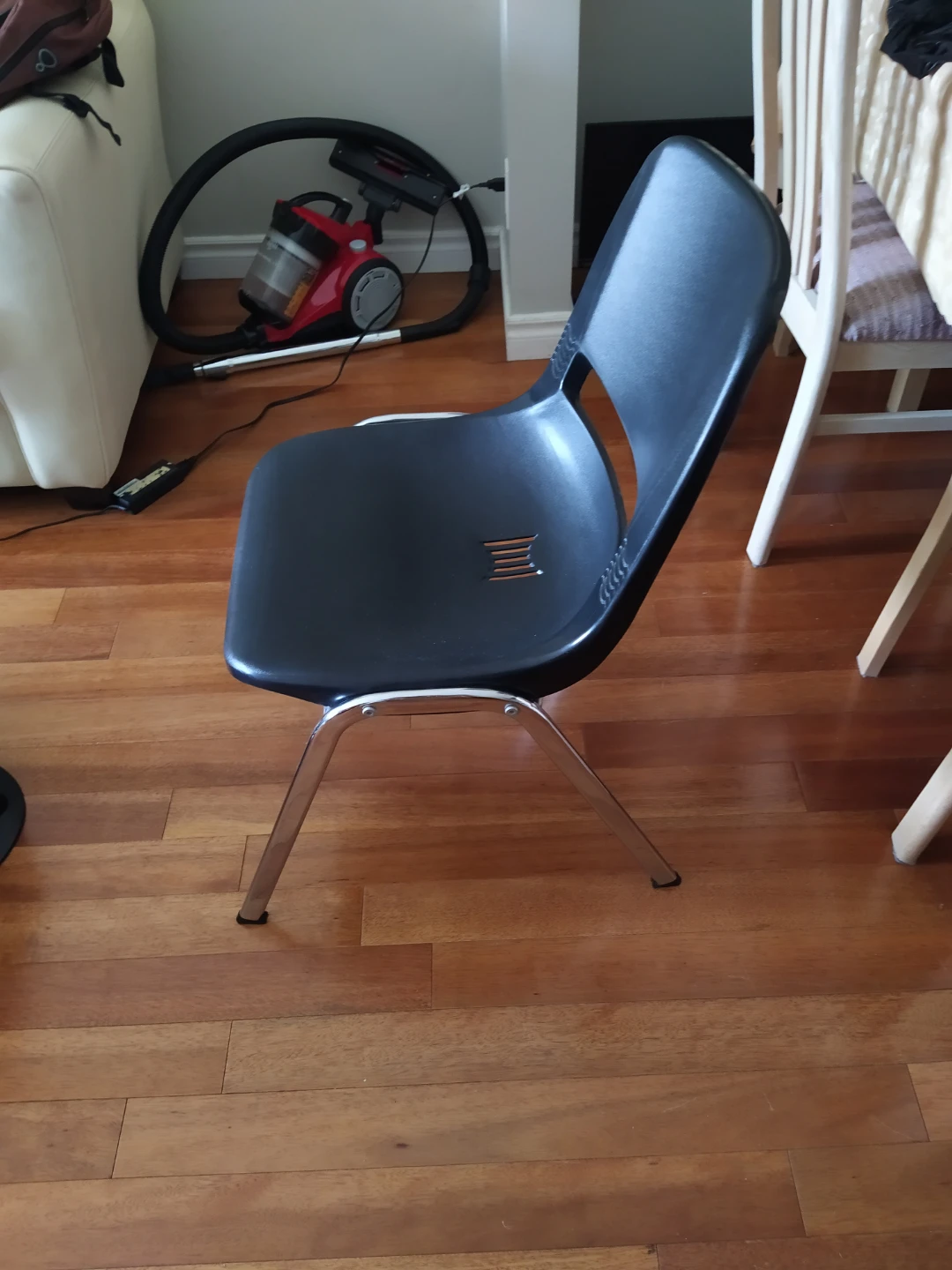 Black plastic stacking chair with chrome legs
