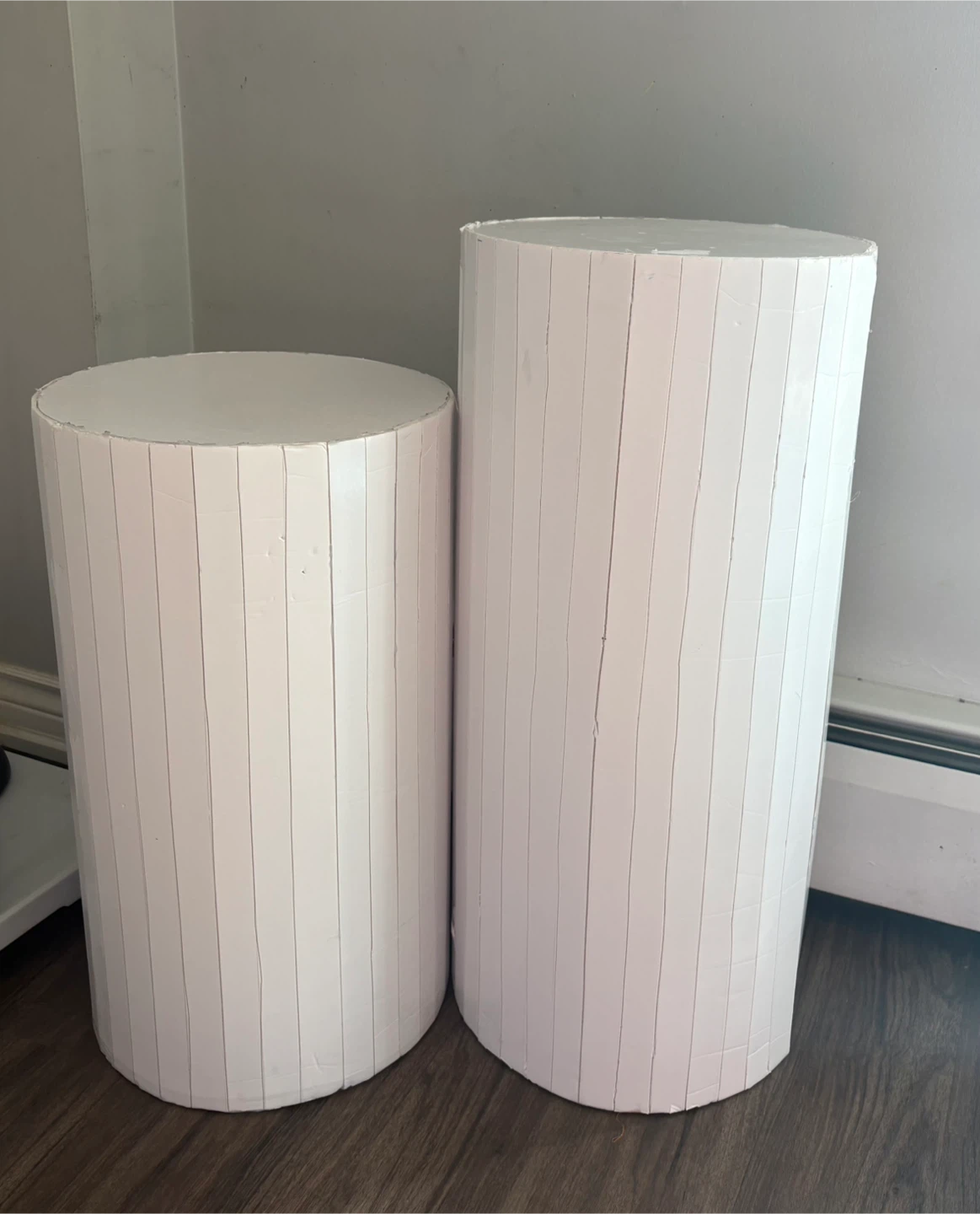 Two white cylindrical display pedestals
