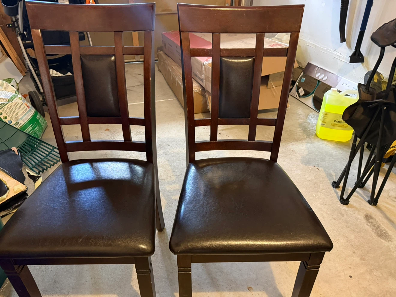 Two dark wood dining chairs with faux leather seats