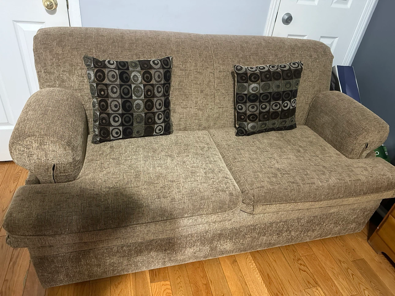 Beige two-seater loveseat (sofa cum bed) with accent cushions