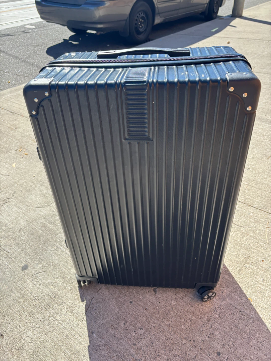 Large check in Calpak black hard-shell suitcase