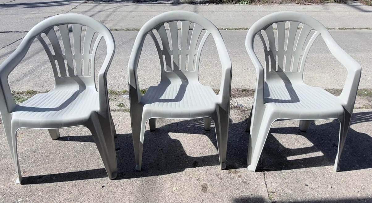 Three light gray plastic patio chairs