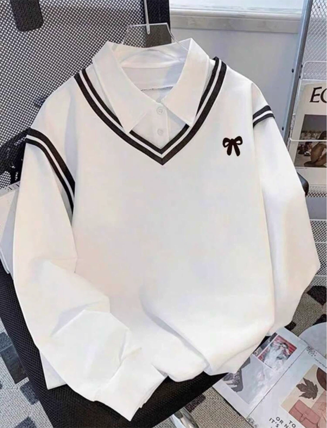 White long-sleeved polo with black bow and collar trim