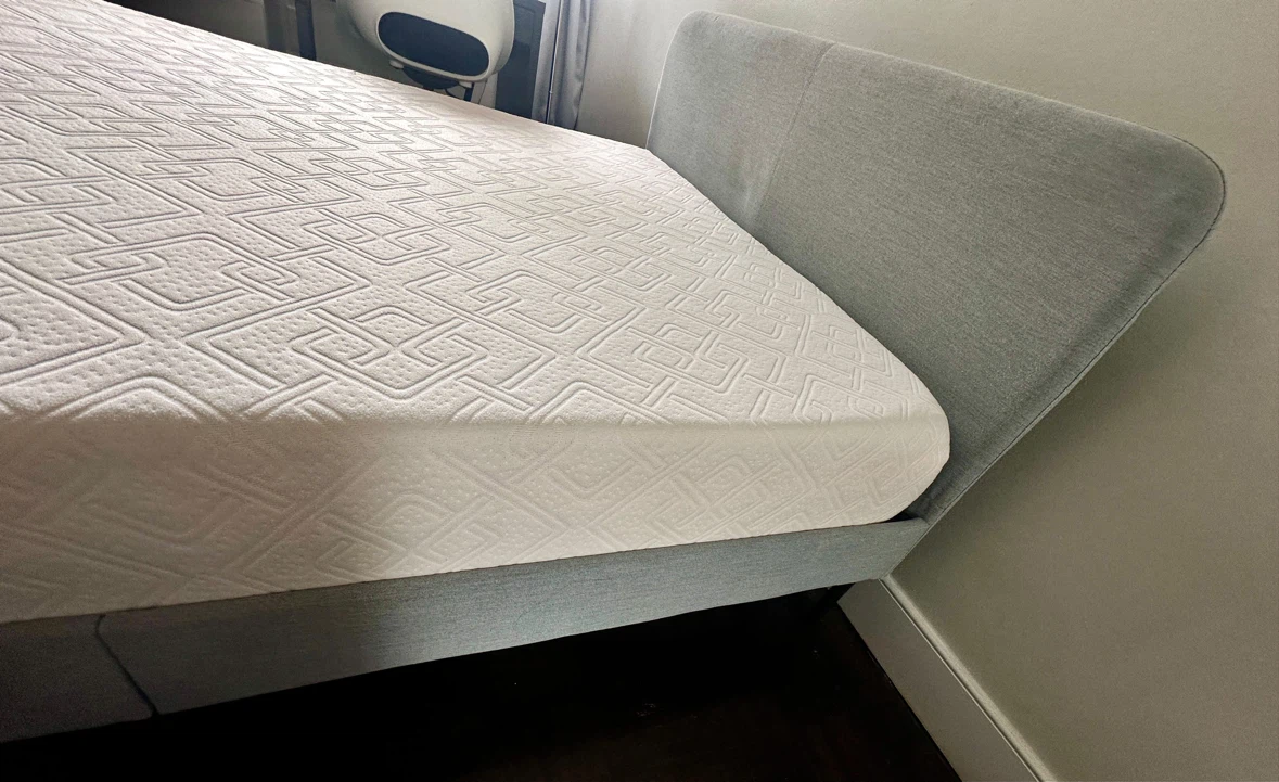 Double size mattress with grey upholstered bed frame.
