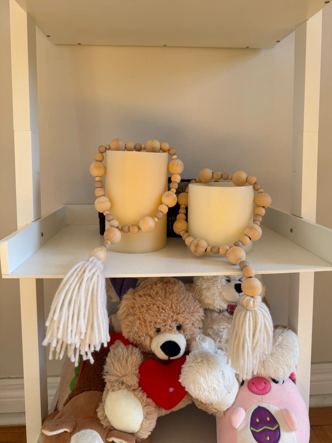 Two cream pillar candles with wooden bead garlands