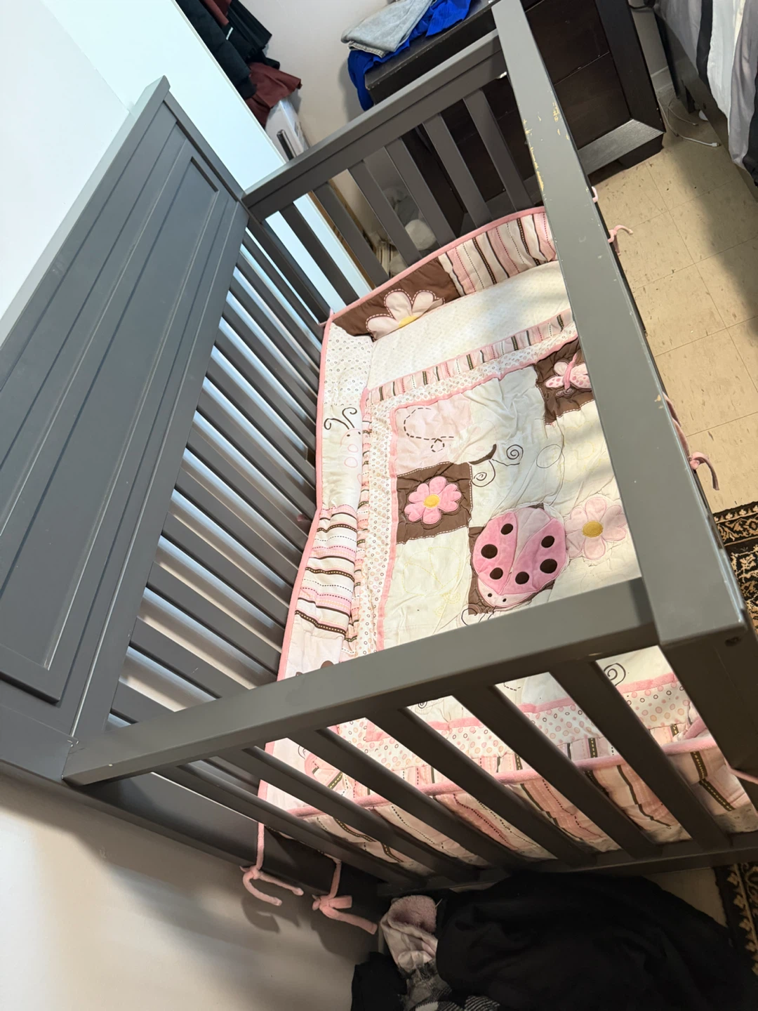 Grey wooden baby crib with mattress and cover everything