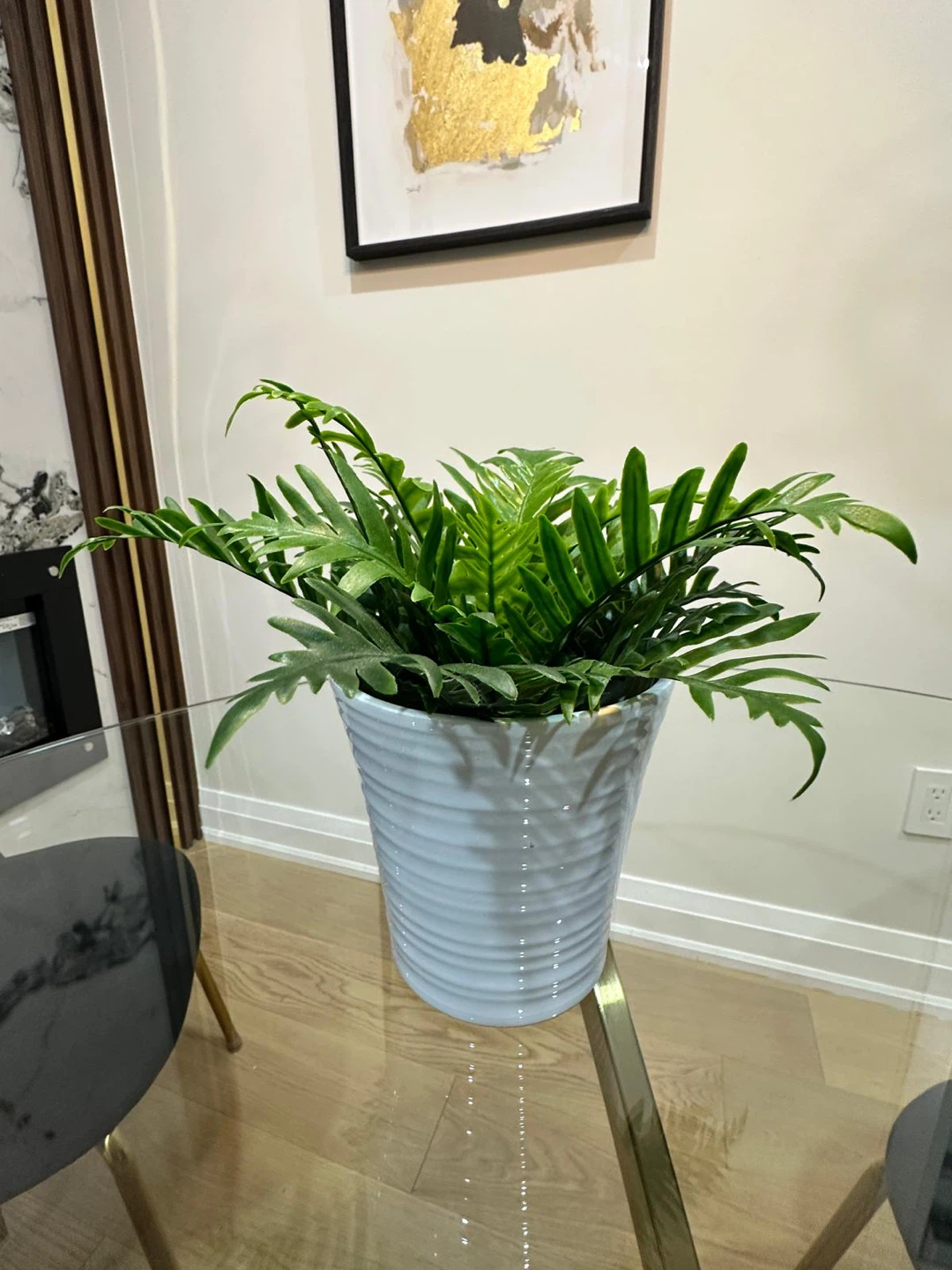 Artificial fern plant in white ribbed pot