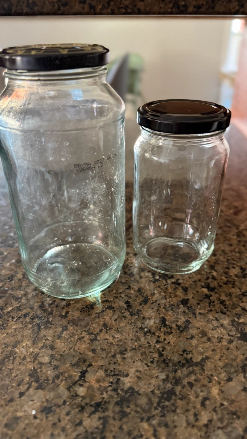Two empty glass jars with black lids