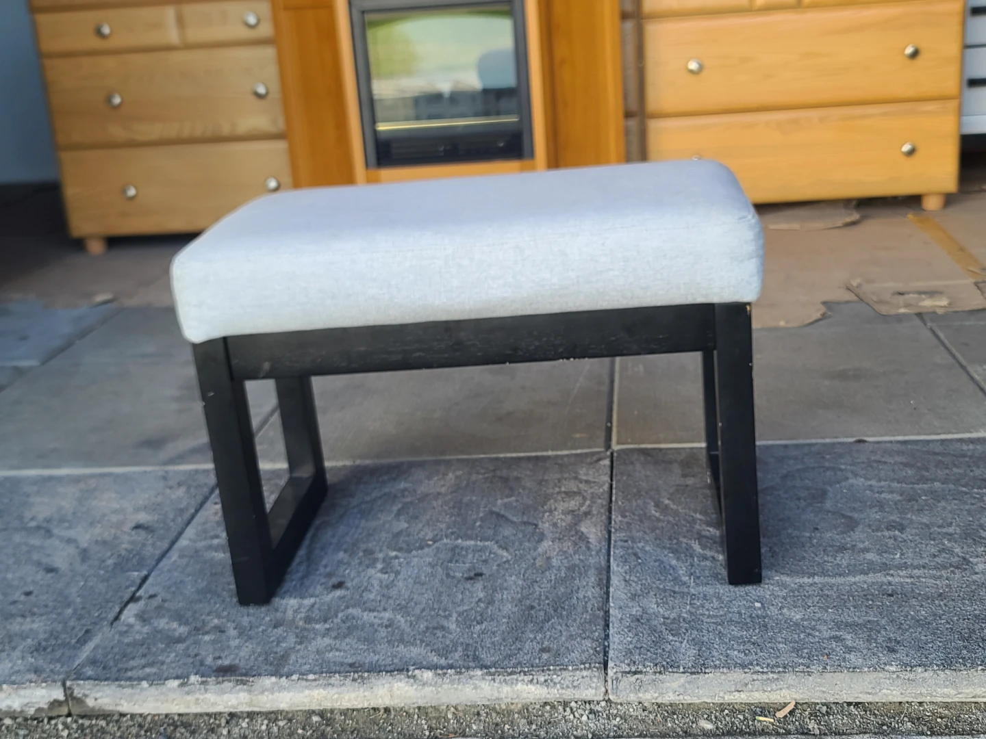 Upholstered footstool with black wooden frame