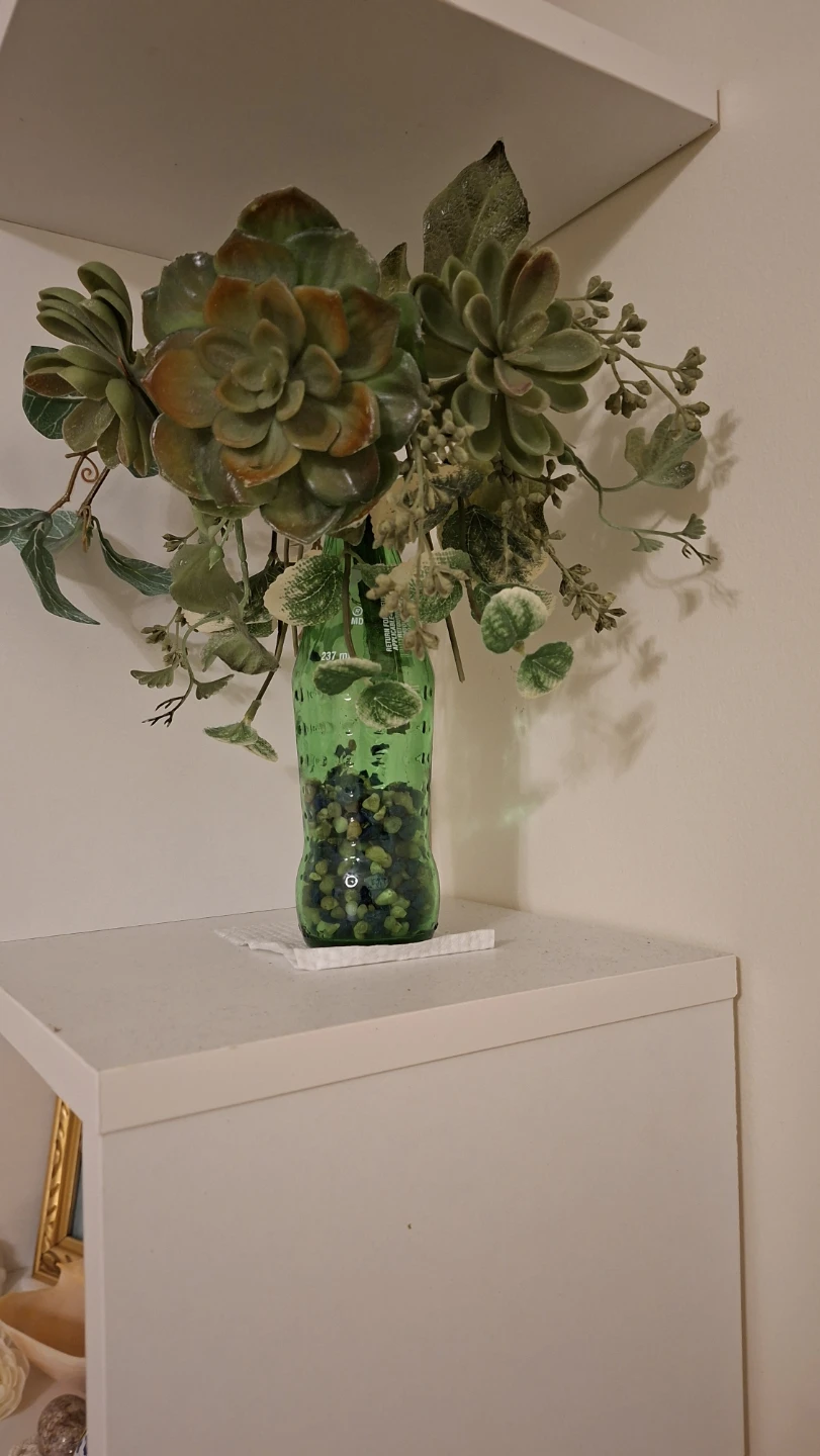 Artificial succulent arrangement in glass bottle