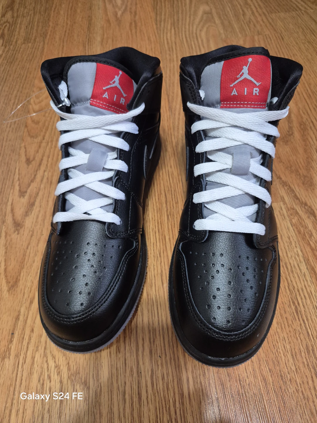 These are authentic Air Jordan 1 Mid sneakers in a black and red