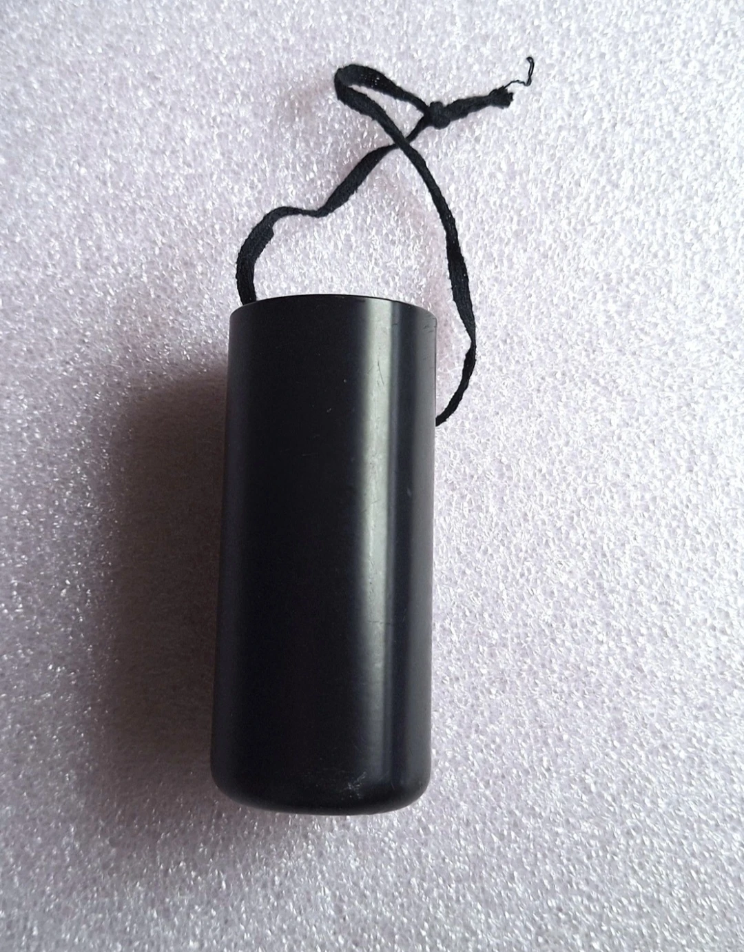 Black cylindrical container with hanging string