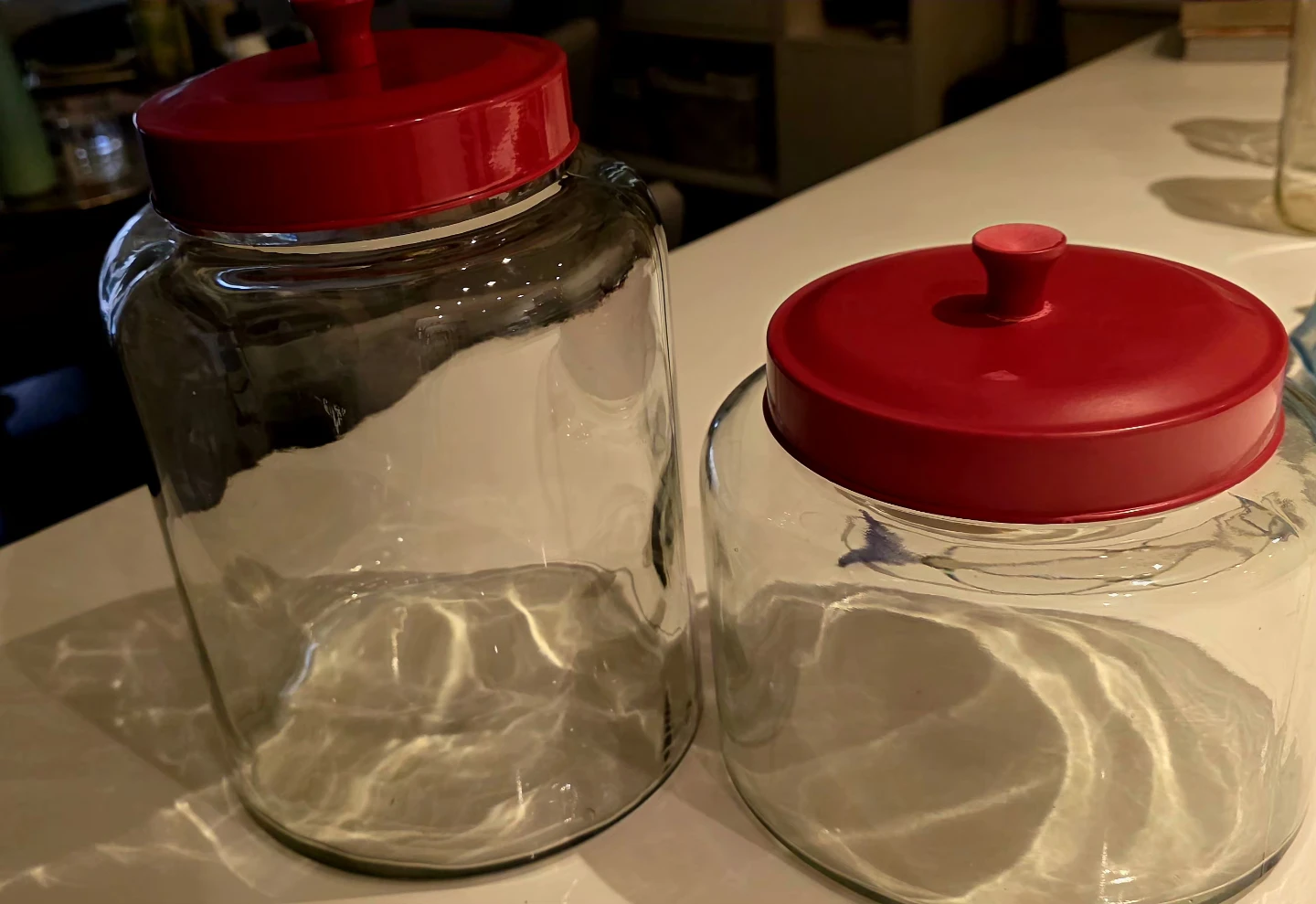 Two Clear Glass Storage Jars with Red Lids