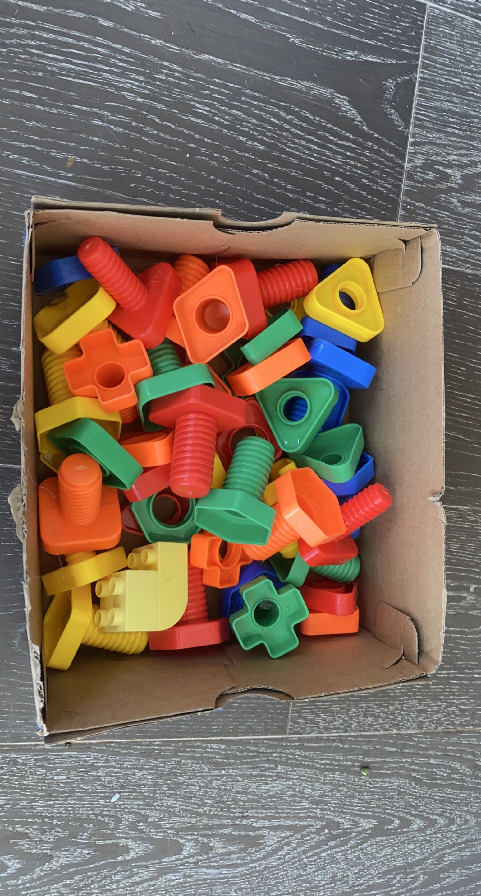 Box of colourful plastic toy building pieces thumbnail