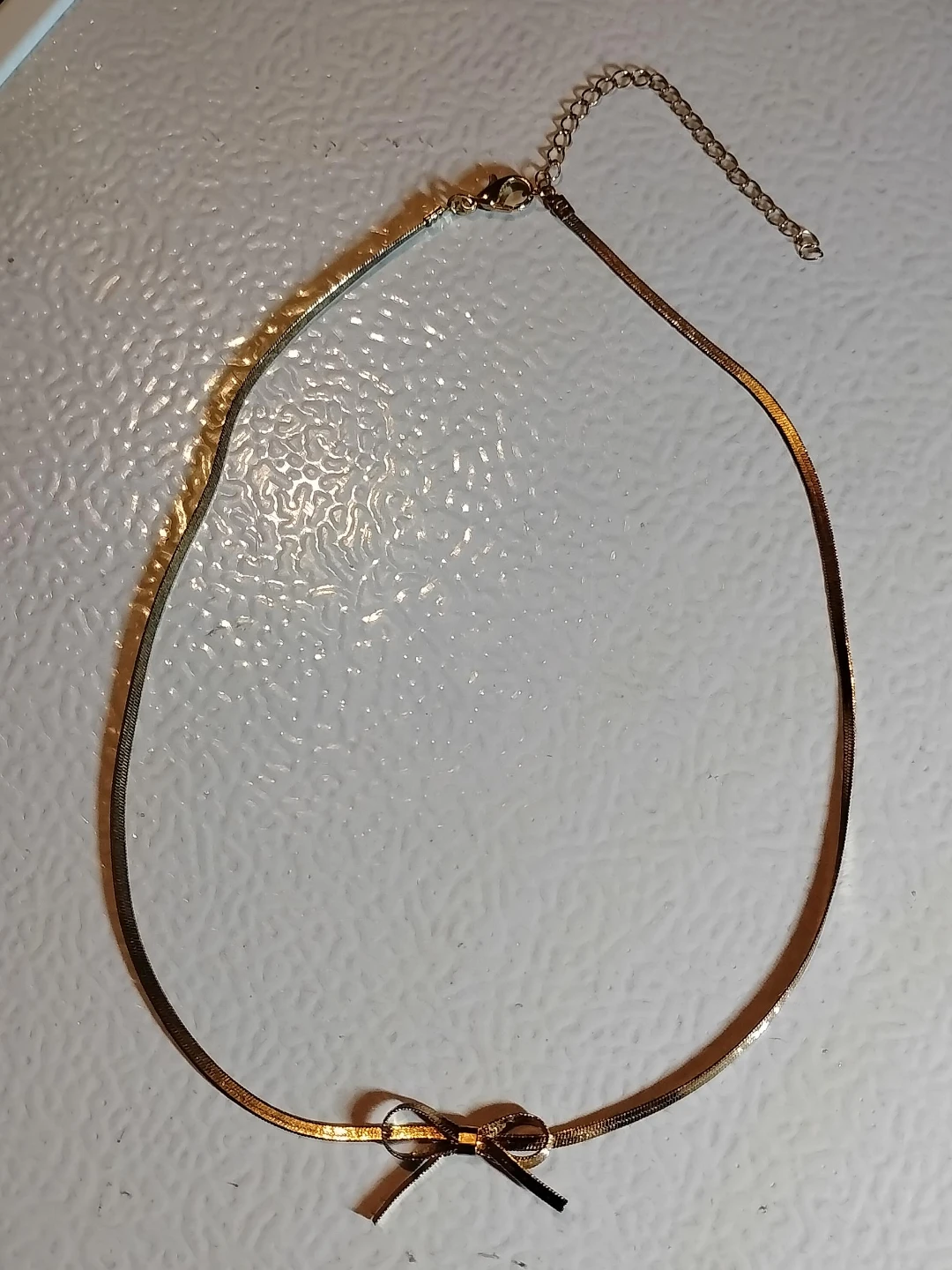 Gold tone herringbone necklace with bow accent