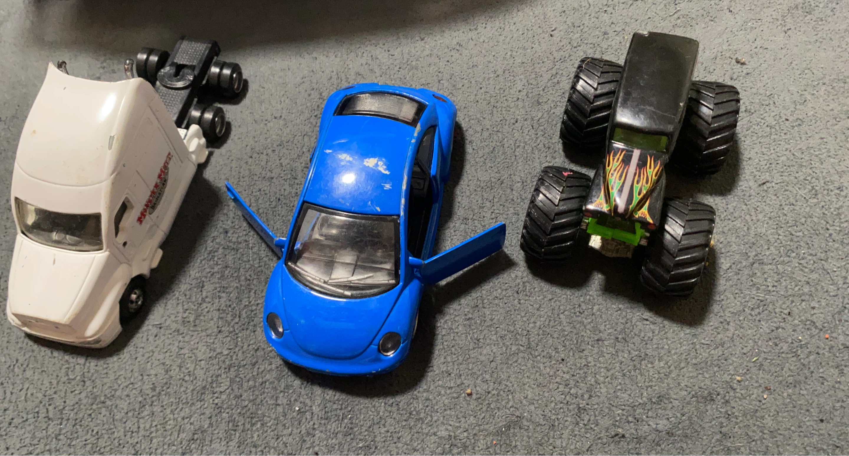 Blue toy car, white truck, and monster truck