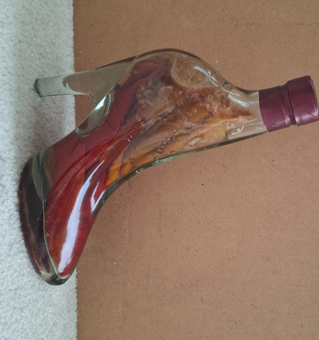 Glass boot-shaped bottle with chili peppers and lemon slices