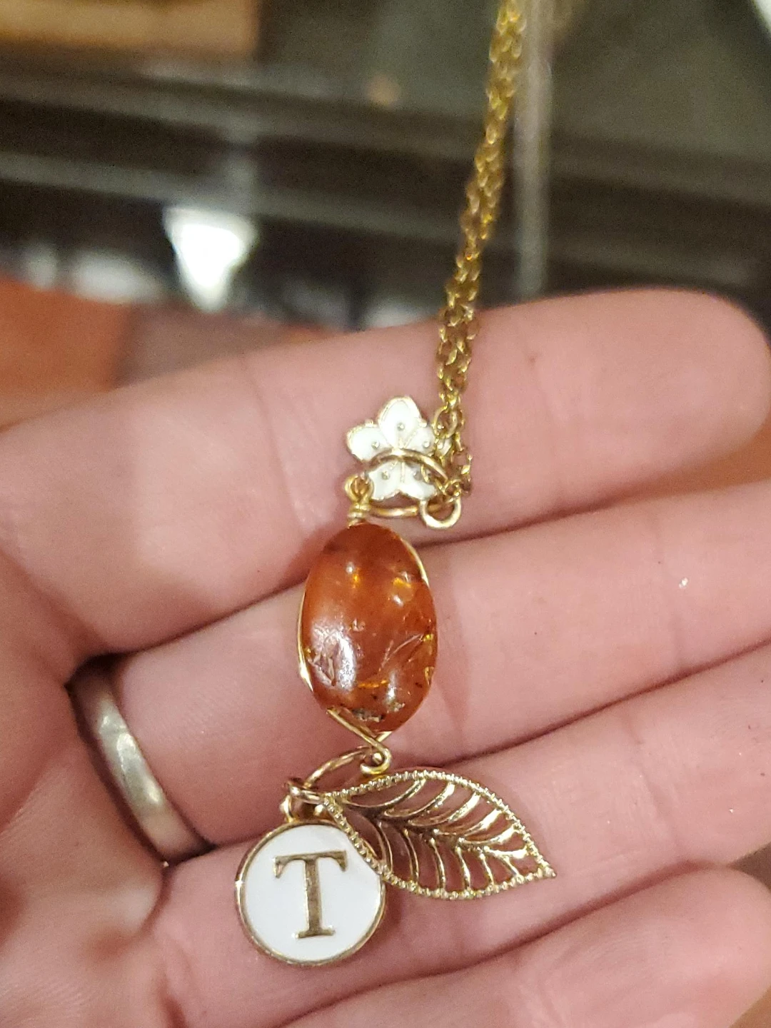 Gold-tone necklace with amber pendant and initial T charm