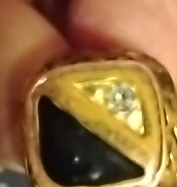 Gold tone ring with black stone and small diamond accent
