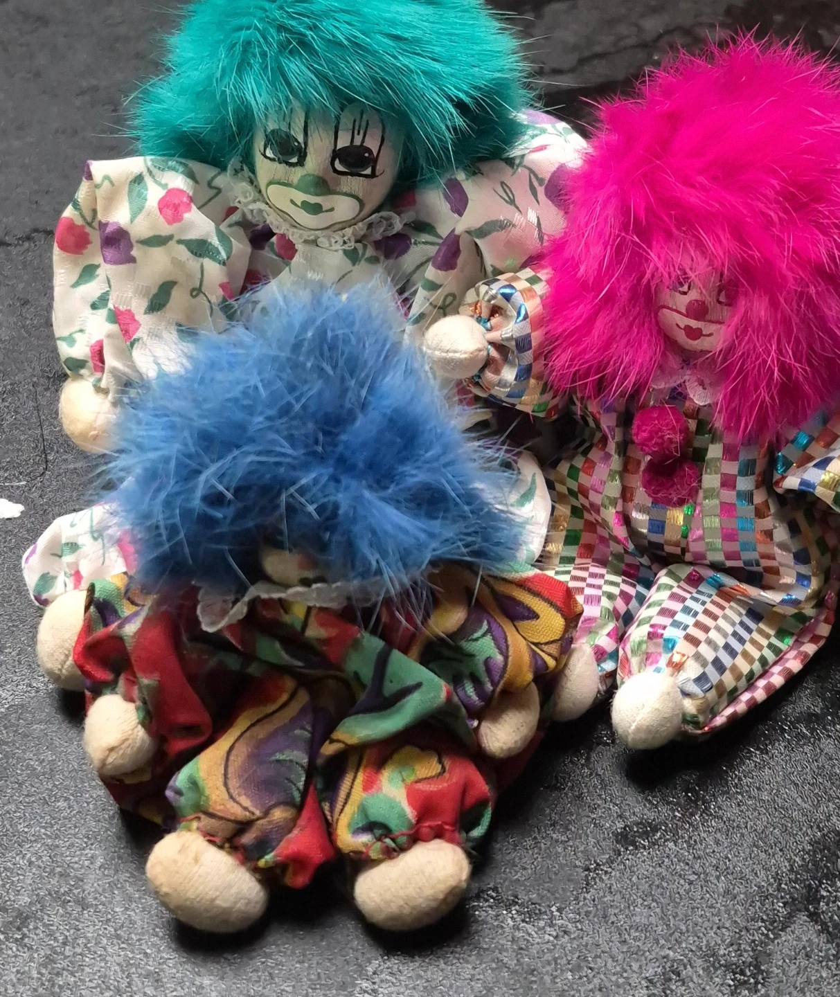 Three plush clown dolls with colourful outfits and fluffy hair