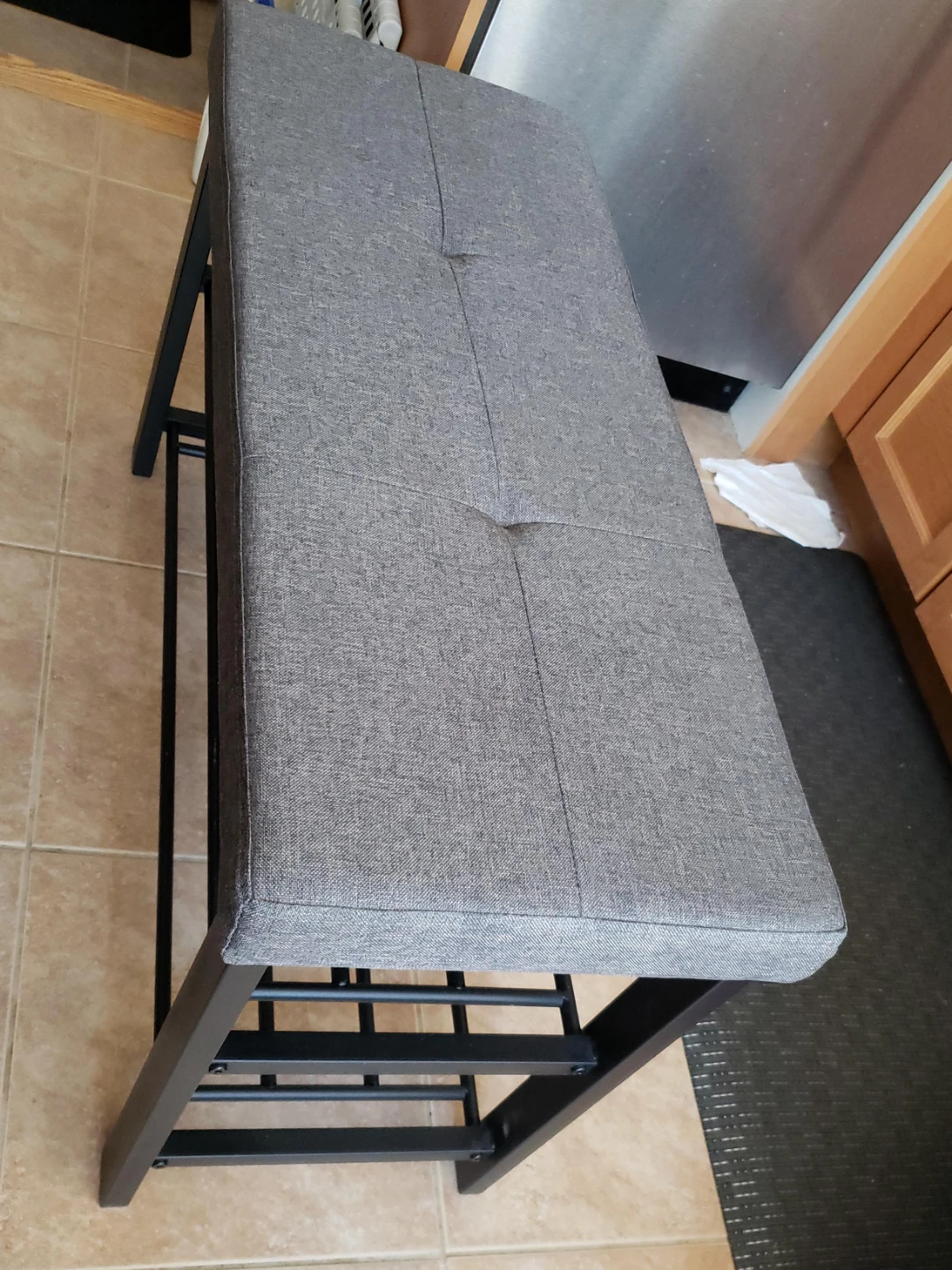 Grey upholstered bench with black metal legs