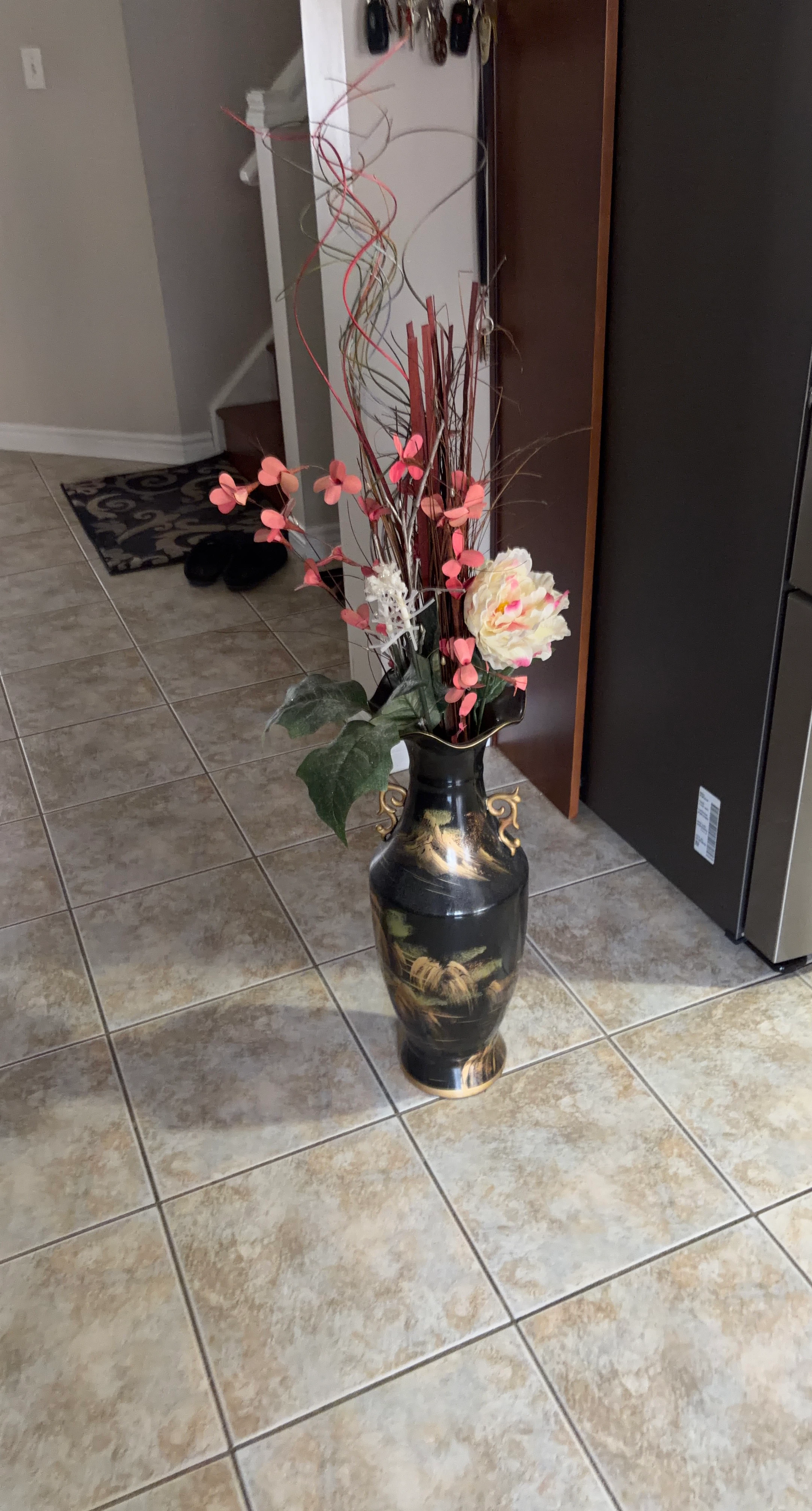 Black and gold floor vase with artificial flowers