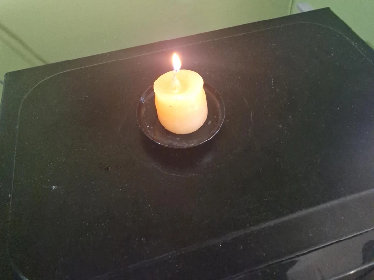 Orange pillar candle on small black plate
