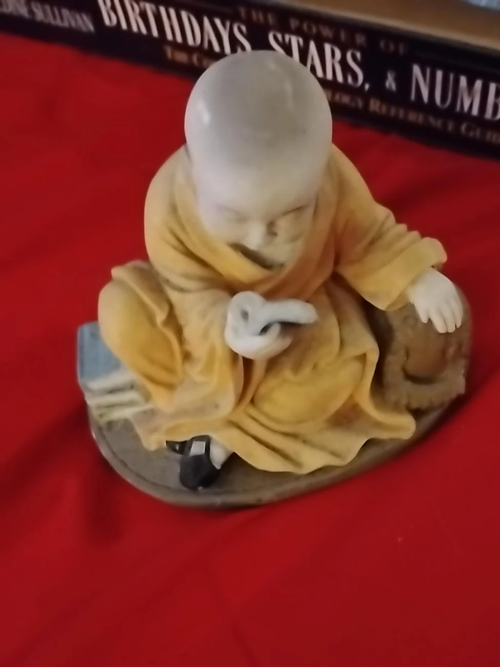 Small monk figurine reading a book